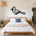Black metal cardinal wall art in a bold silhouette style, mounted above a bed in a bright bedroom.