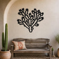 Black metal Cholla cactus wall art with spiny branch cutouts, mounted on a stucco wall above a wooden bench in a southwestern-style patio.