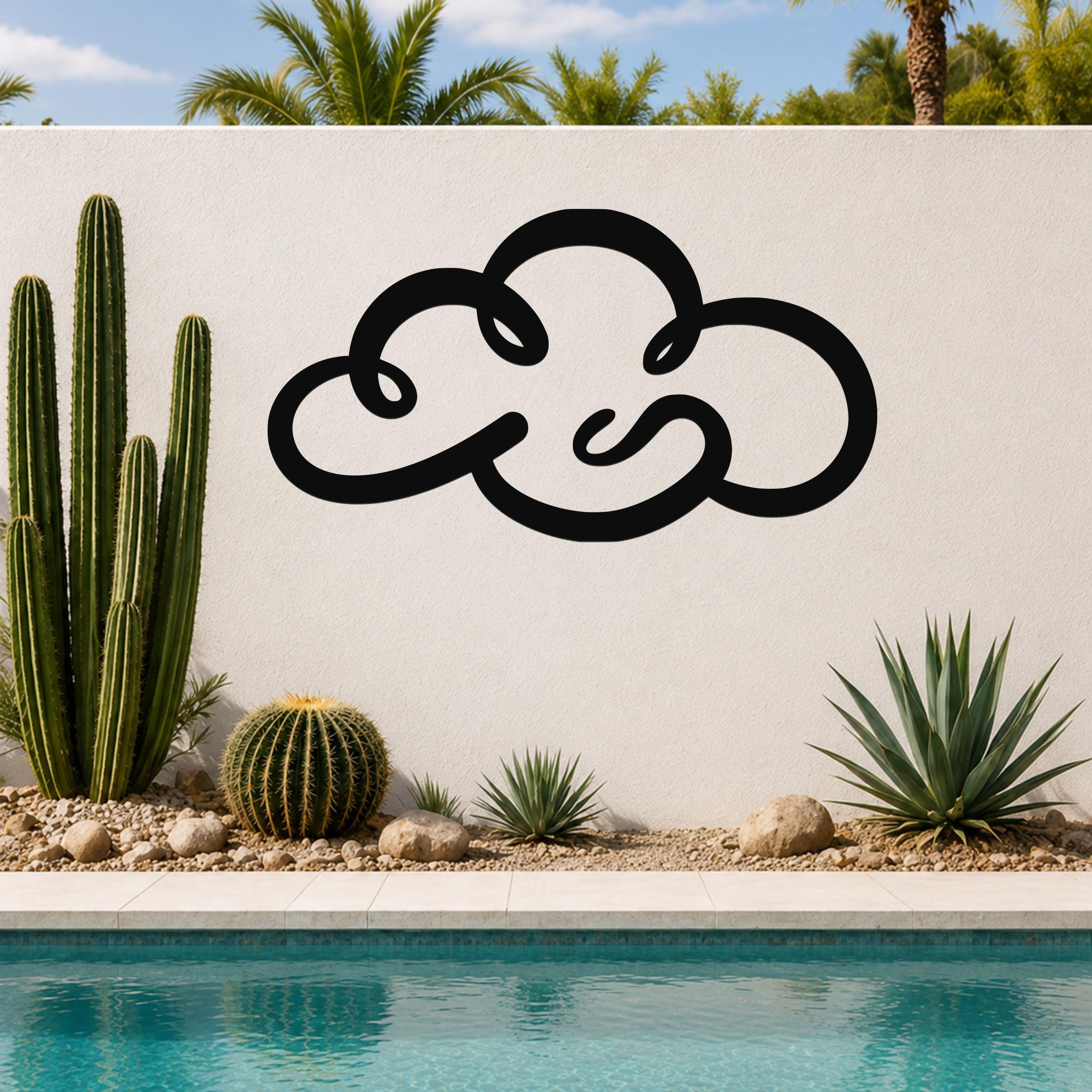 Black metal cloud wall art with flowing silhouette design, mounted on a white outdoor wall beside a pool and desert plants.