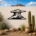 Black metal cloud wall art with flowing silhouette cutouts, mounted on a white outdoor wall above a desert garden with cacti and rocks.