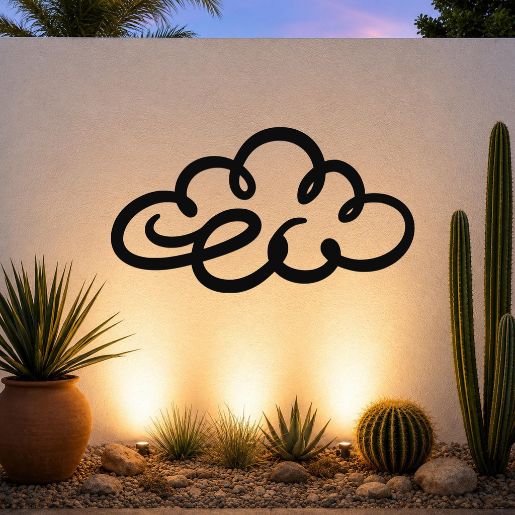 Black metal cloud wall art with flowing silhouette cutouts, mounted on a textured outdoor wall above a desert garden with cacti and warm uplighting.