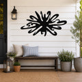 Black metal sea urchin wall art with organic spines and cutout details, mounted on a white shiplap wall above a wooden bench on a porch.
