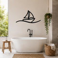 Black metal sailboat wall art with wave cutout, mounted on a bathroom wall above a freestanding tub.