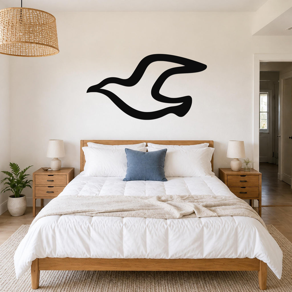 Black metal seagull wall art with a flowing silhouette, mounted above a wooden bed in a bright bedroom.