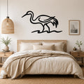 Black metal crane wall art with flowing line cutouts, mounted above a bed in a neutral bedroom.