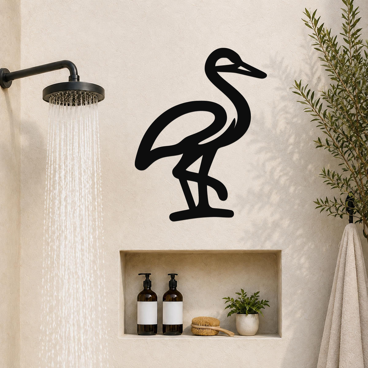 Black metal crane wall art silhouette mounted on a bathroom wall above a built-in shelf, with a showerhead to the left and a plant to the right.