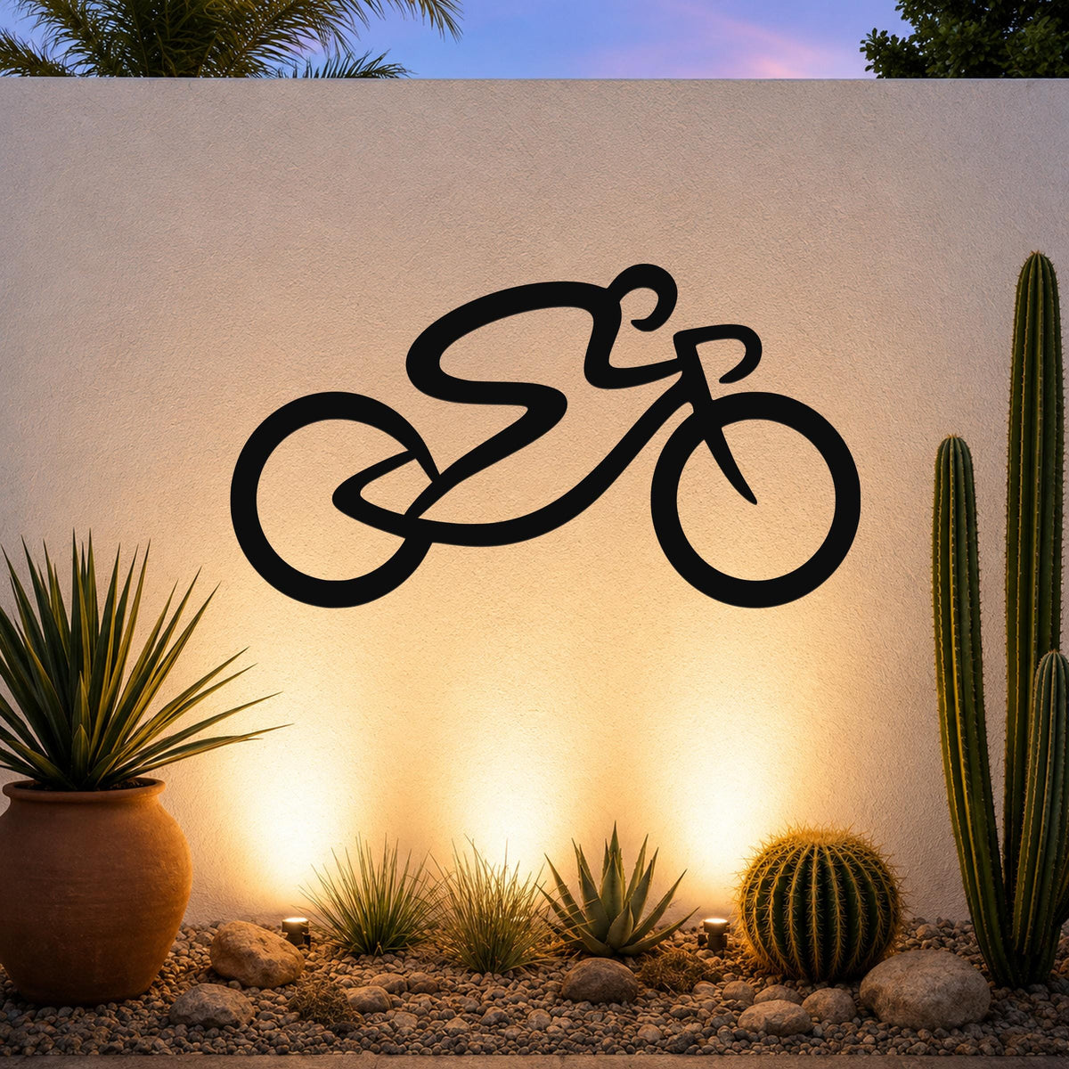 Black metal bicycle wall art with a bold silhouette design, mounted on an outdoor wall above a desert garden with cacti and warm uplighting.