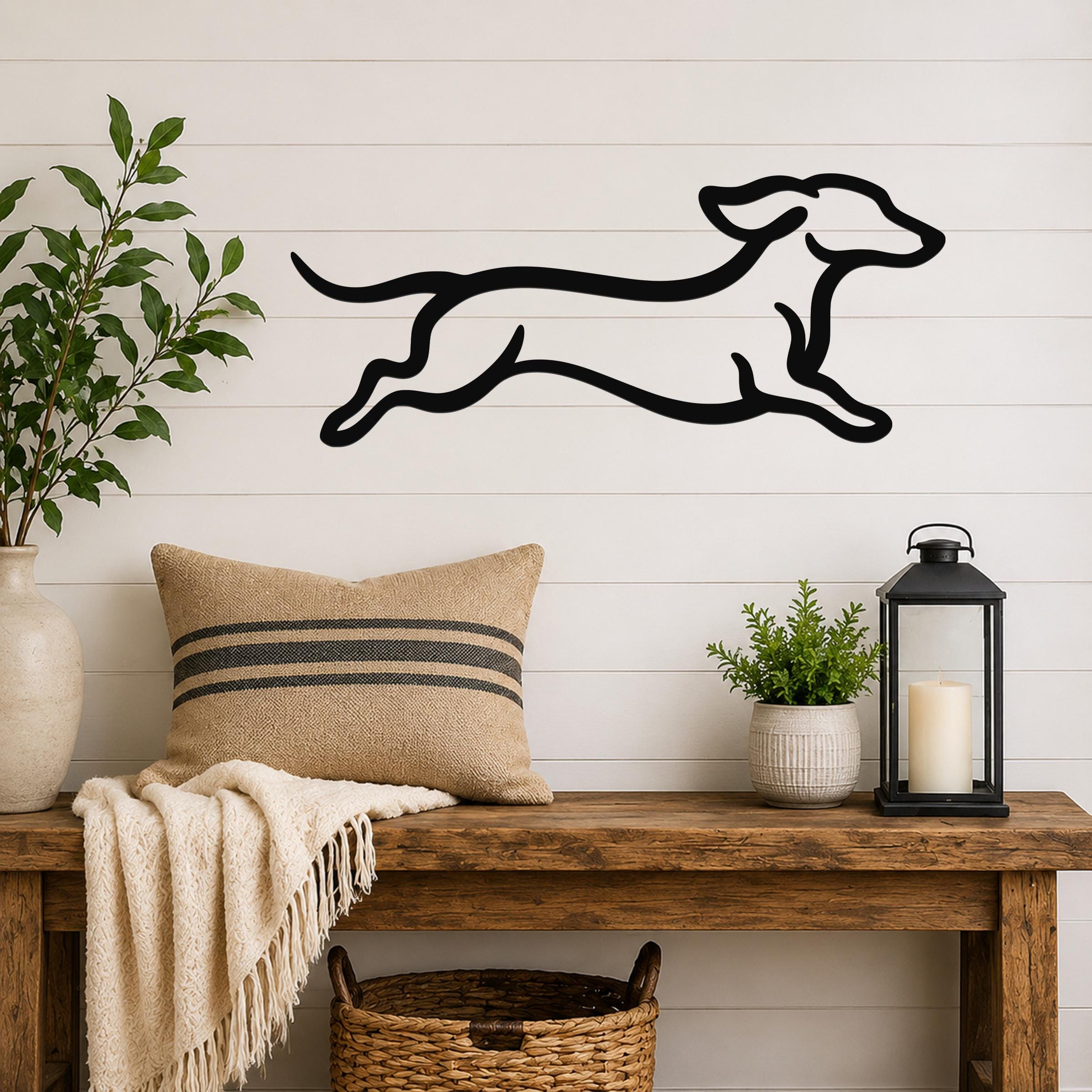 Black metal dachshund wall art with a running silhouette, mounted on a white shiplap wall above a wooden bench in a living room.