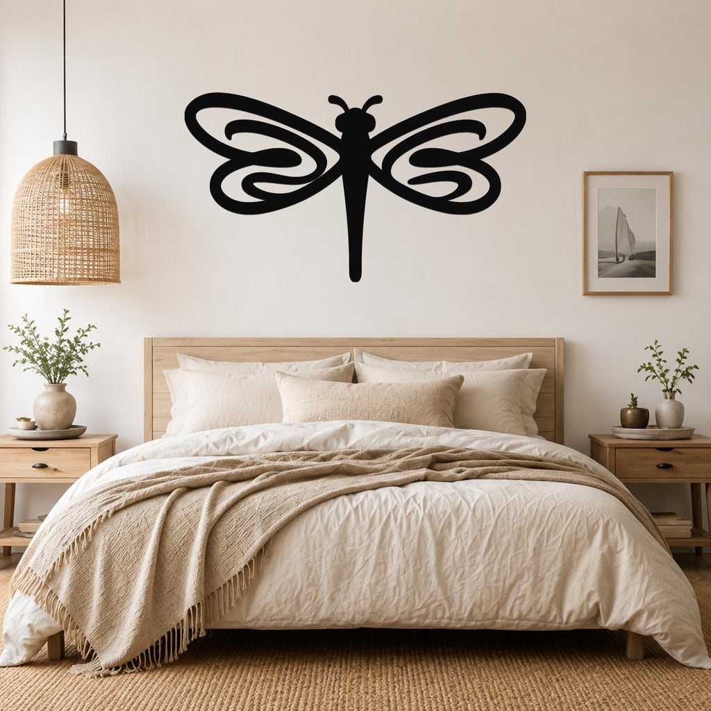 Black metal dragonfly wall art with flowing wing cutouts, mounted above a wooden bed in a neutral bedroom.