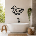 Black metal duck wall art silhouette mounted on a bathroom wall above a freestanding tub, with a hanging plant and woven basket nearby.