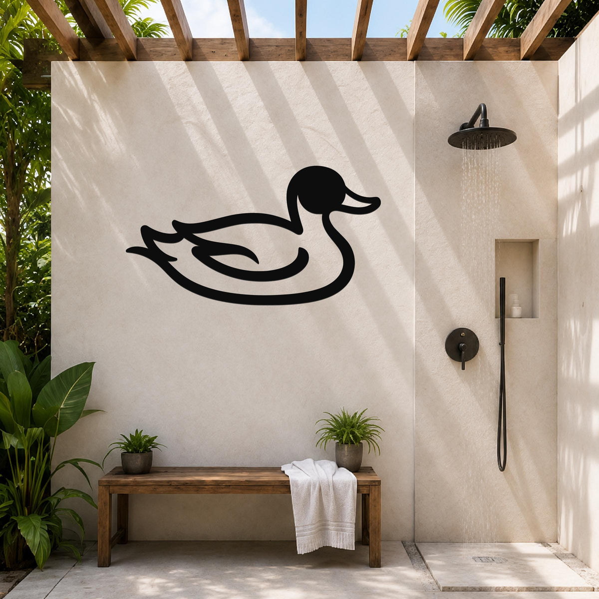 Black metal duck wall art silhouette mounted on a beige outdoor shower wall, above a wooden bench with potted plants and a towel, under a wooden pergola.