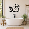 Black metal duck wall art silhouette with wavy water lines, mounted on a bathroom wall above a freestanding tub.