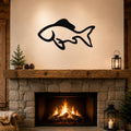 Black metal fish wall art with a graceful silhouette design, mounted above a stone fireplace in a rustic living room.