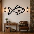Black metal fish silhouette wall art mounted on a white shiplap wall above a wooden console table in a rustic living room.