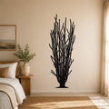 Black metal ocotillo wall art with spiny branch cutouts, mounted on a beige bedroom wall above a woven rug.
