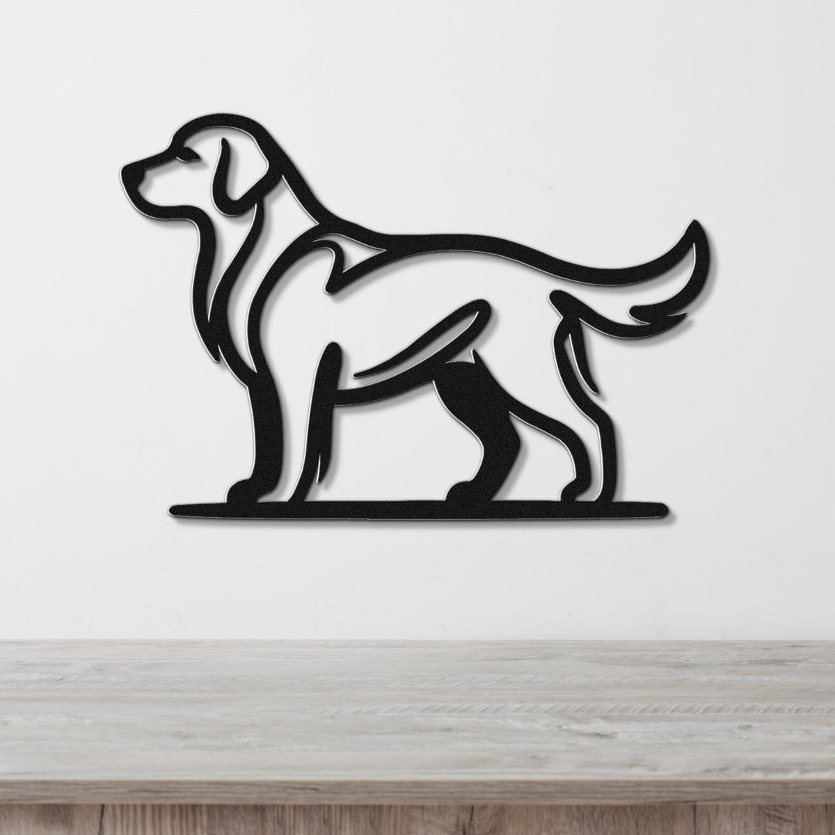 Black metal dog silhouette wall art of a standing Golden Retriever, mounted on a white wall above a light wood surface.