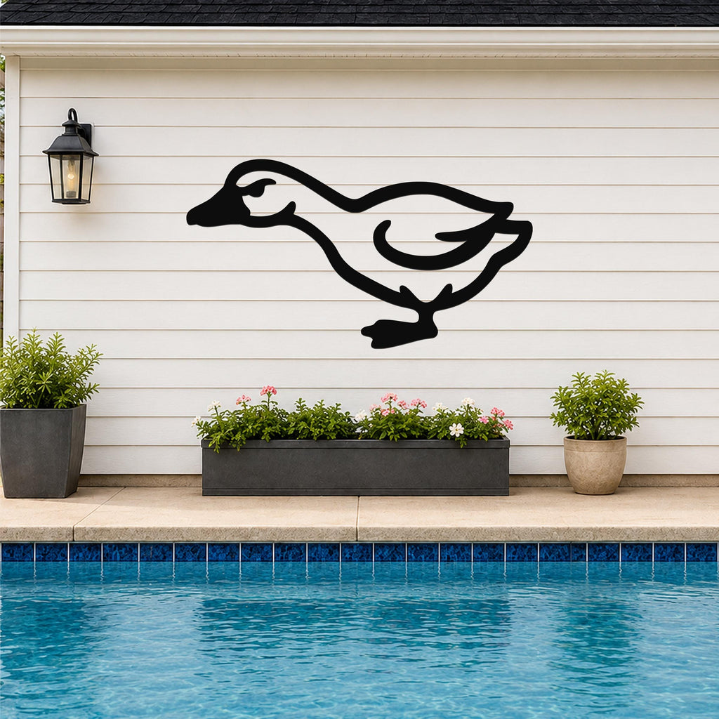 Black metal goose wall art silhouette mounted on a white horizontal siding wall above a pool, with a black lantern and potted plants nearby.