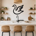 Black metal goose wall art silhouette with wing cutouts, mounted above a kitchen counter in a modern rustic kitchen.
