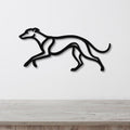 Black metal greyhound wall art with a sleek silhouette design, mounted on a white wall above a light wood surface.