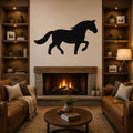 Black metal horse wall art silhouette with motion-line cutouts, mounted above a fireplace in a rustic living room.