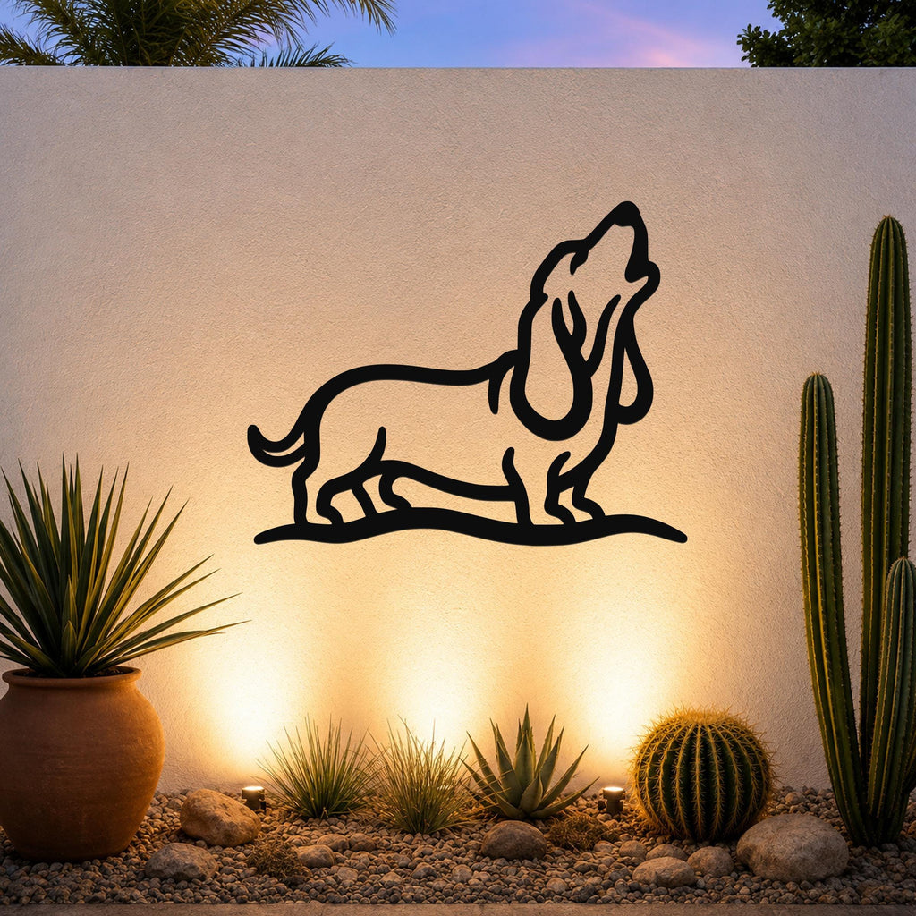 Black metal wall art featuring a bold silhouette of a howling basset hound, mounted on an outdoor wall above a desert garden with cacti and warm uplighting.