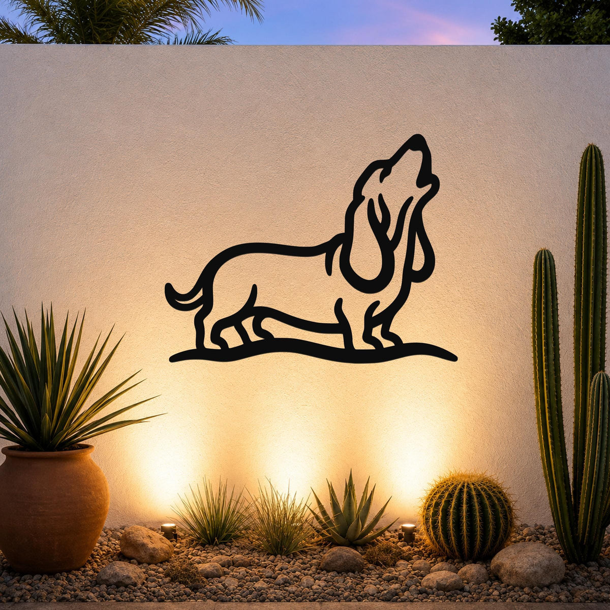 Black metal wall art featuring a bold silhouette of a howling basset hound, mounted on an outdoor wall above a desert garden with cacti and warm uplighting.