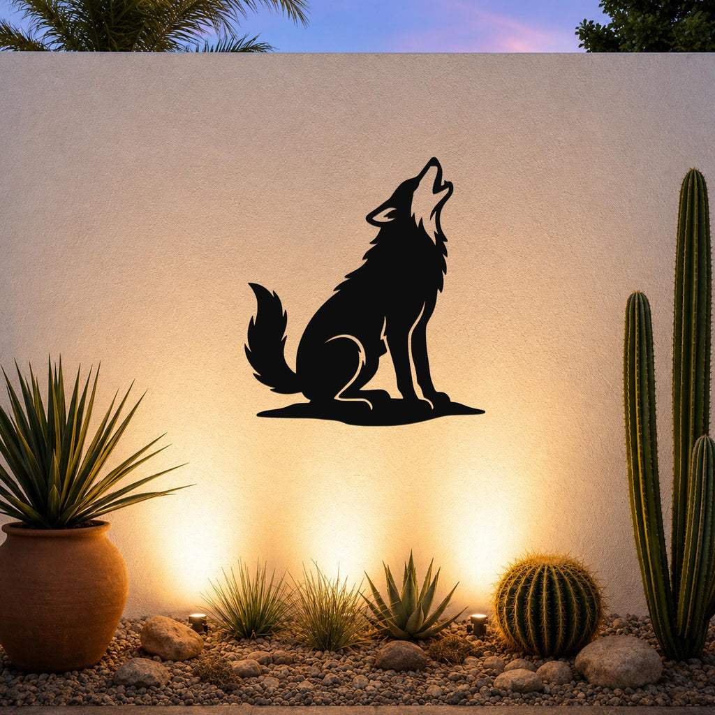 Black metal coyote wall art in a howling silhouette, mounted on an outdoor wall above a desert garden with cacti and warm uplighting.