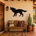 Black metal coyote wall art in a howling silhouette, mounted on a stucco wall above a wooden bench in a rustic patio entryway.