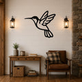 Black metal hummingbird wall art with motion-line cutouts, mounted on a white shiplap wall above a wooden console table in a living room.