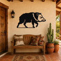 Black metal javelina wall art silhouette mounted on a stucco wall above a wooden bench in a covered patio entryway.