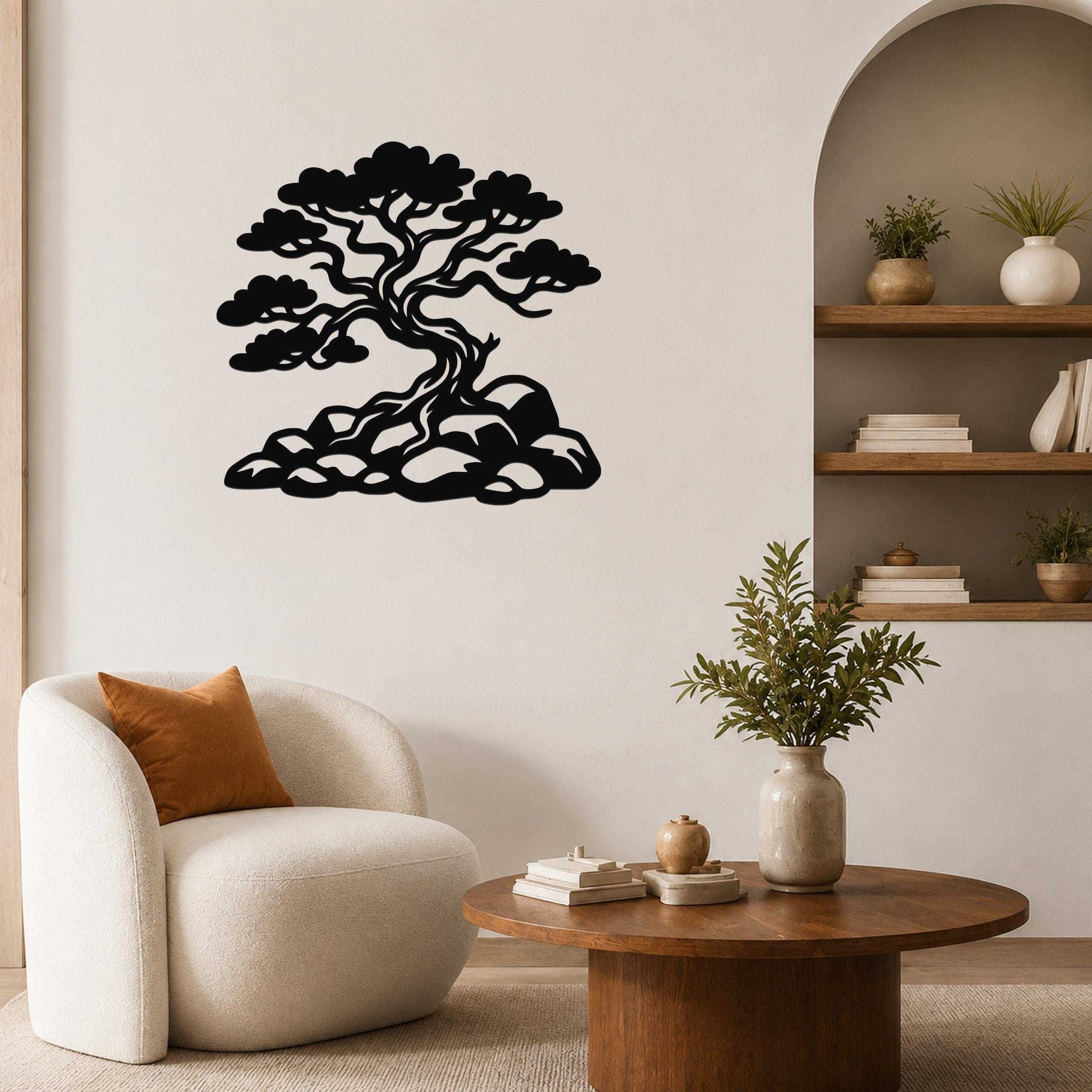Black metal wall art silhouette of a bonsai-style juniper tree with rocky base, mounted on a living room wall above a round wooden coffee table.