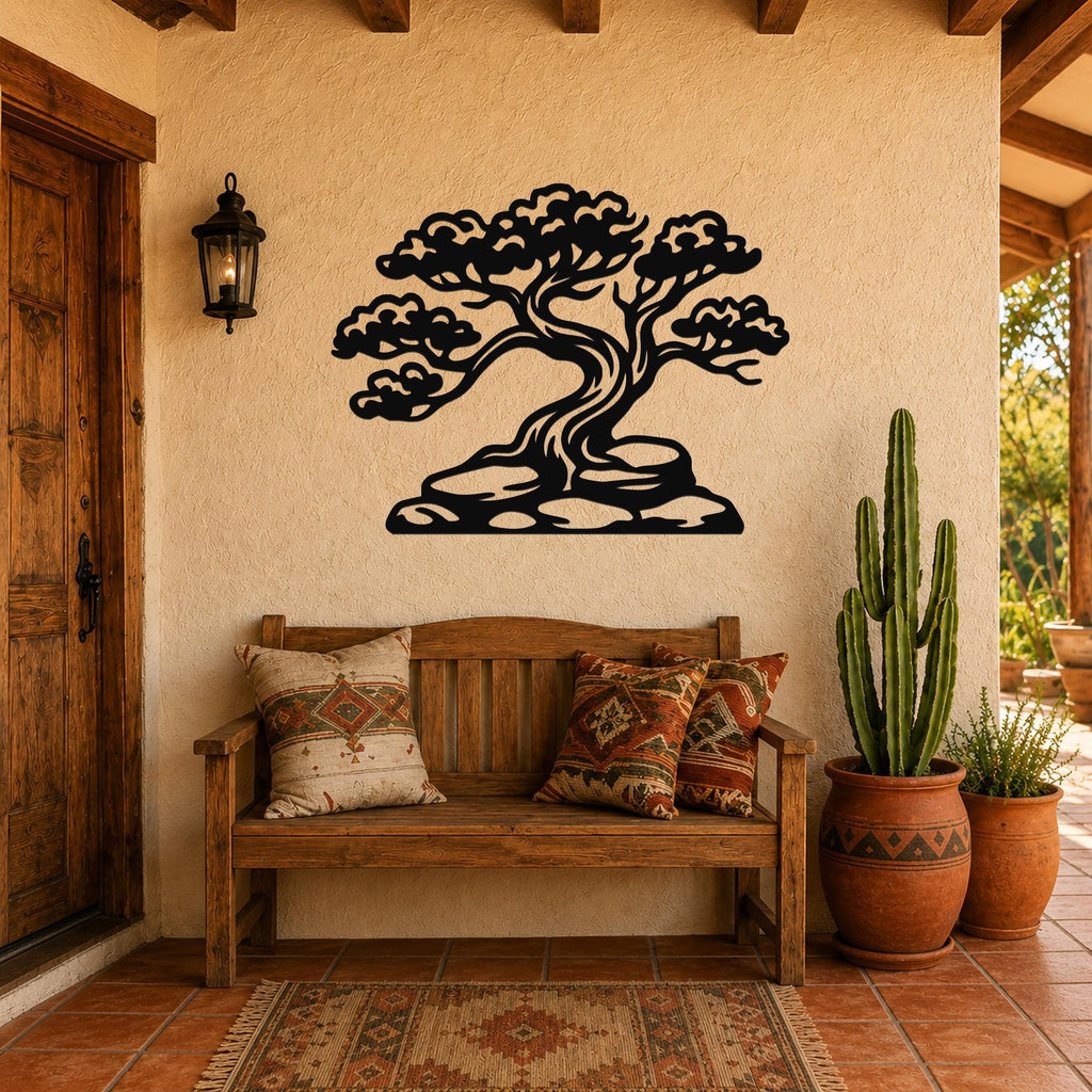Black metal wall art silhouette of a juniper tree with detailed branches and roots, mounted on a stucco wall above a wooden bench in a patio entryway.