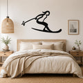 Black metal wall art of a skier silhouette with ski poles, mounted above a bed in a bedroom.