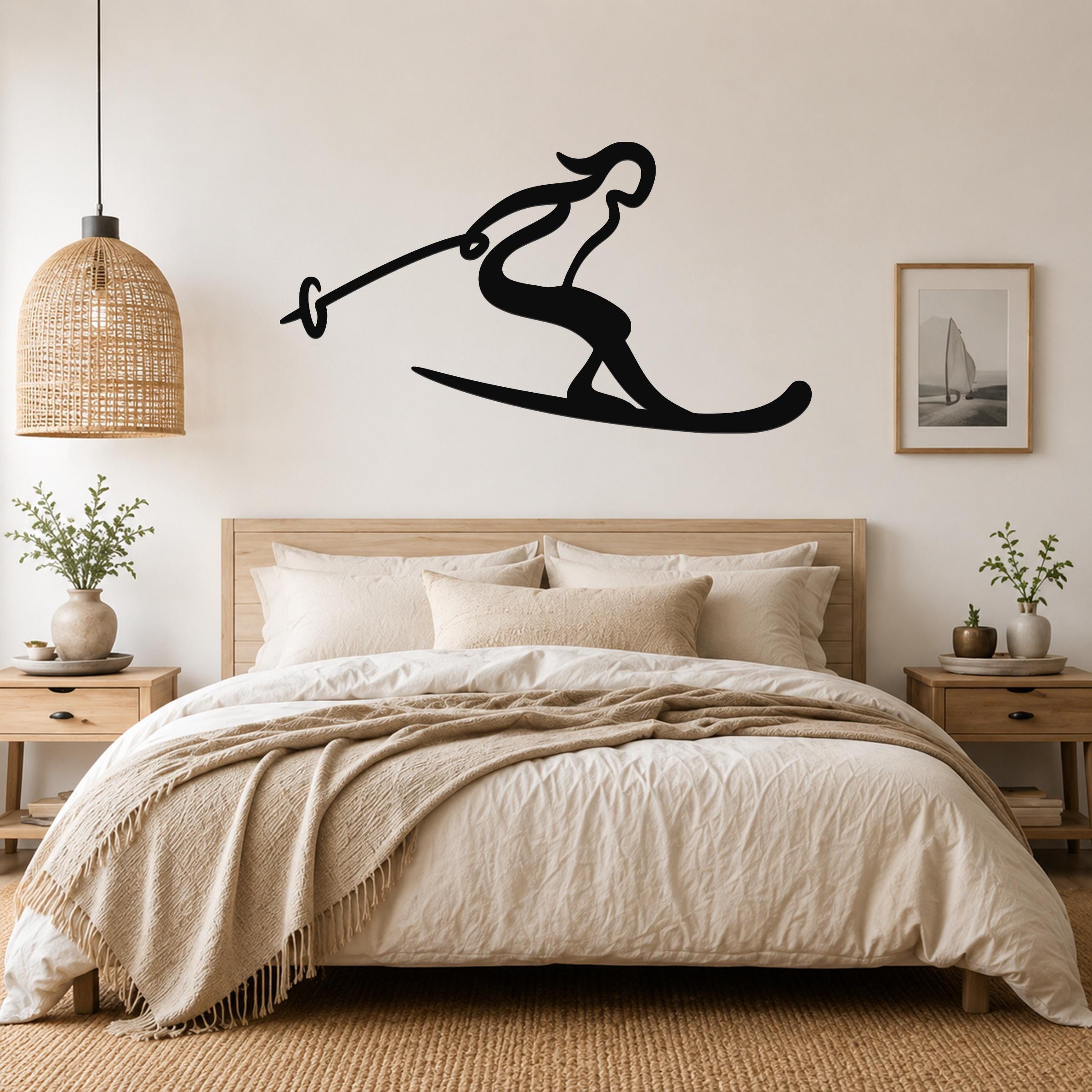 Black metal wall art of a skier silhouette with ski poles, mounted above a bed in a bedroom.