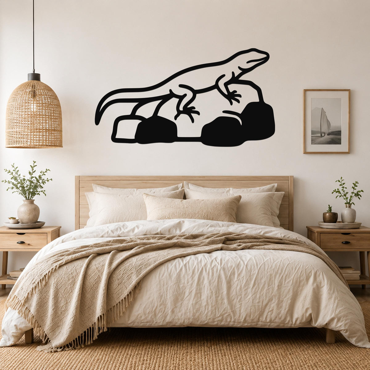Black metal lizard wall art silhouette with internal cutout details, mounted above a bed in a neutral bedroom.