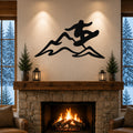 Black metal wall art featuring a snowboarder silhouette in motion over mountain peaks, mounted above a stone fireplace in a living room.
