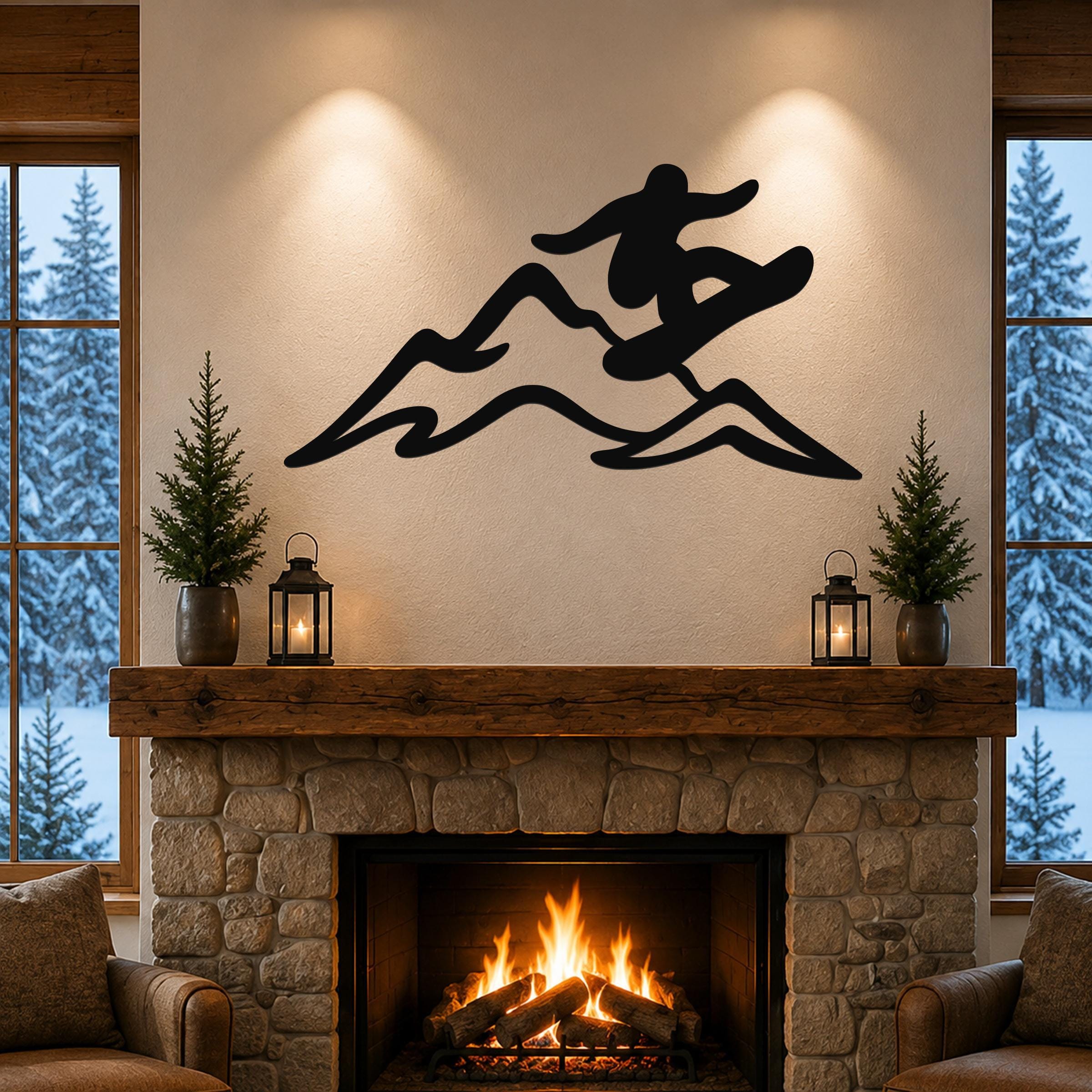 Black metal wall art featuring a snowboarder silhouette in motion over mountain peaks, mounted above a stone fireplace in a living room.
