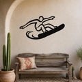 Black metal wall art silhouette of a snowboarder in motion, mounted on a beige stucco wall above a wooden bench in a patio setting.