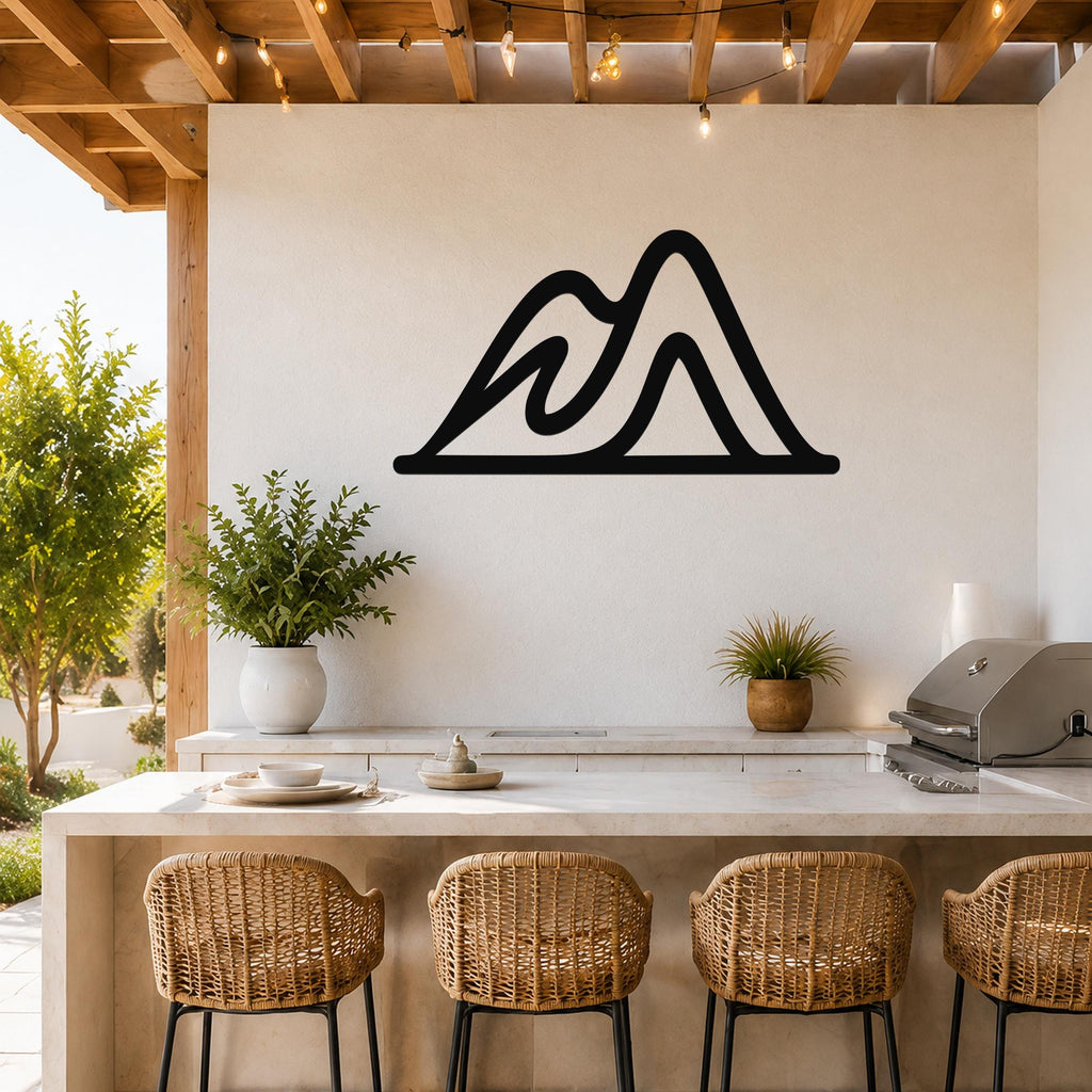 Black metal mountain silhouette wall art with layered peaks, mounted on a white wall above a kitchen counter in a bright outdoor patio space.