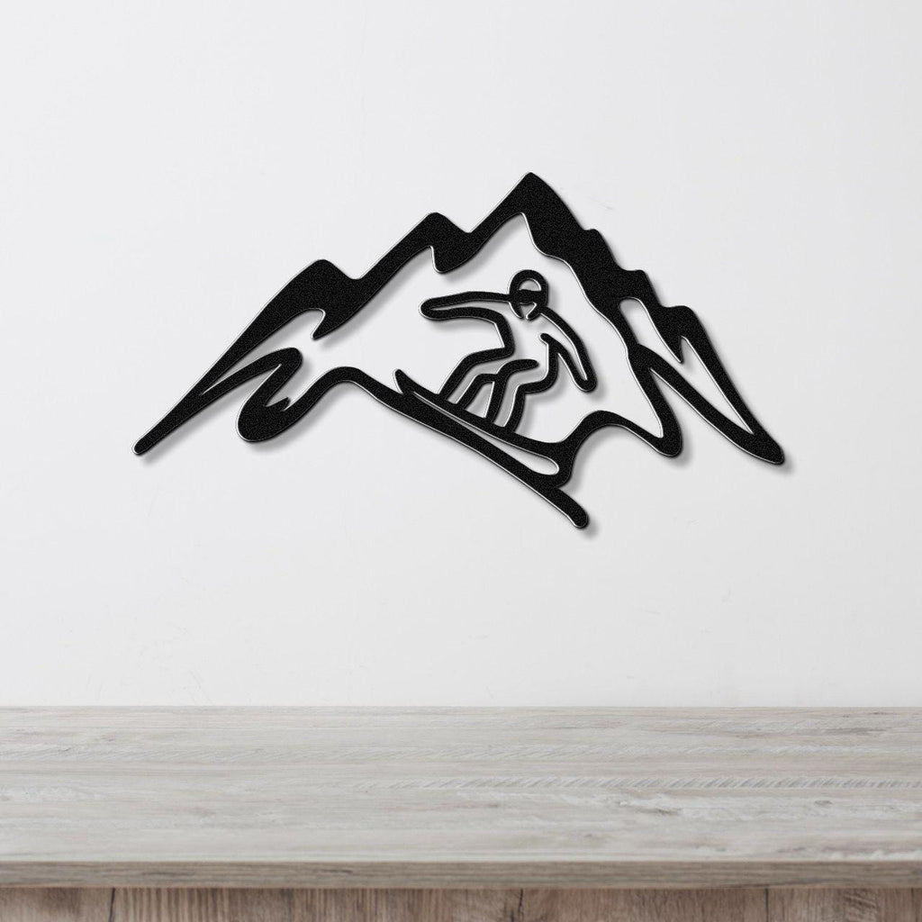 Black metal wall art featuring a snowboarder silhouette within a mountain range cutout, mounted on a white wall above a light wood counter.
