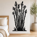 Black metal ocotillo wall art with leafy branch cutouts, mounted on a bedroom wall above a bed.