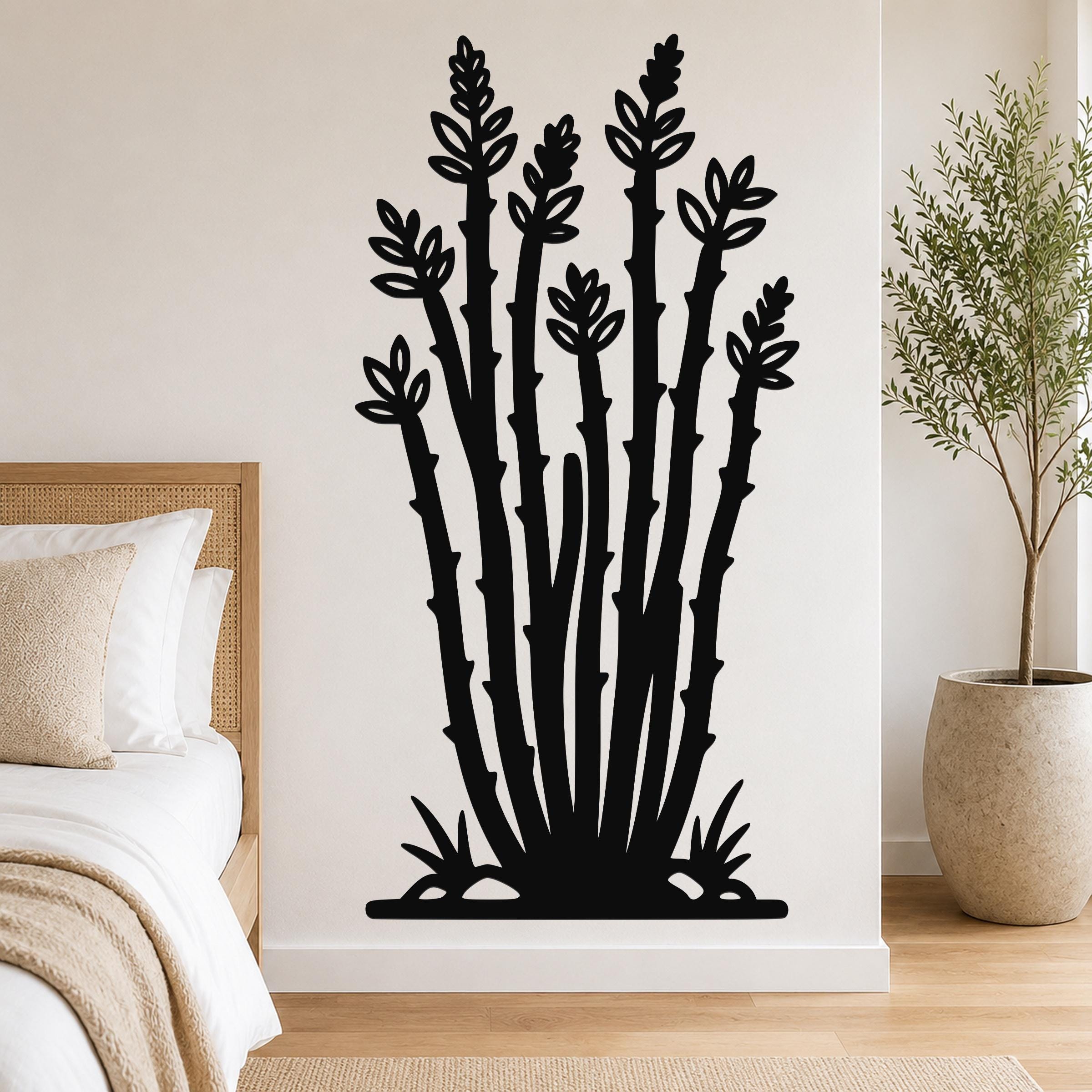 Black metal ocotillo wall art with leafy branch cutouts, mounted on a bedroom wall above a bed.