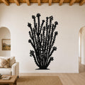 Black metal ocotillo wall art with spiny branches and flower cutouts, mounted on a living room wall above a sofa.