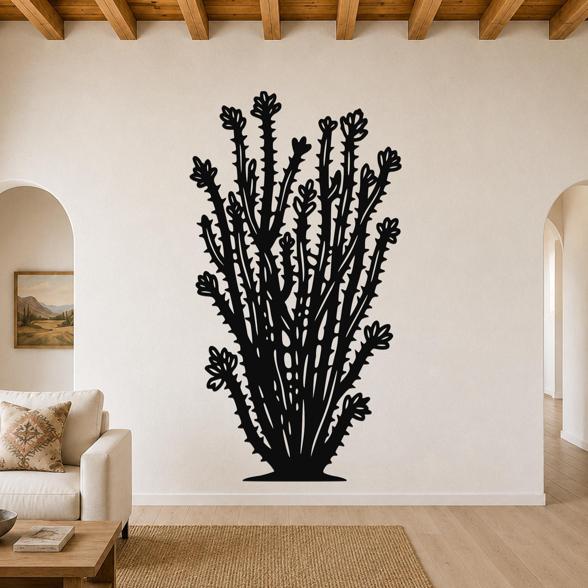 Black metal ocotillo wall art with spiny branches and flower cutouts, mounted on a living room wall above a sofa.