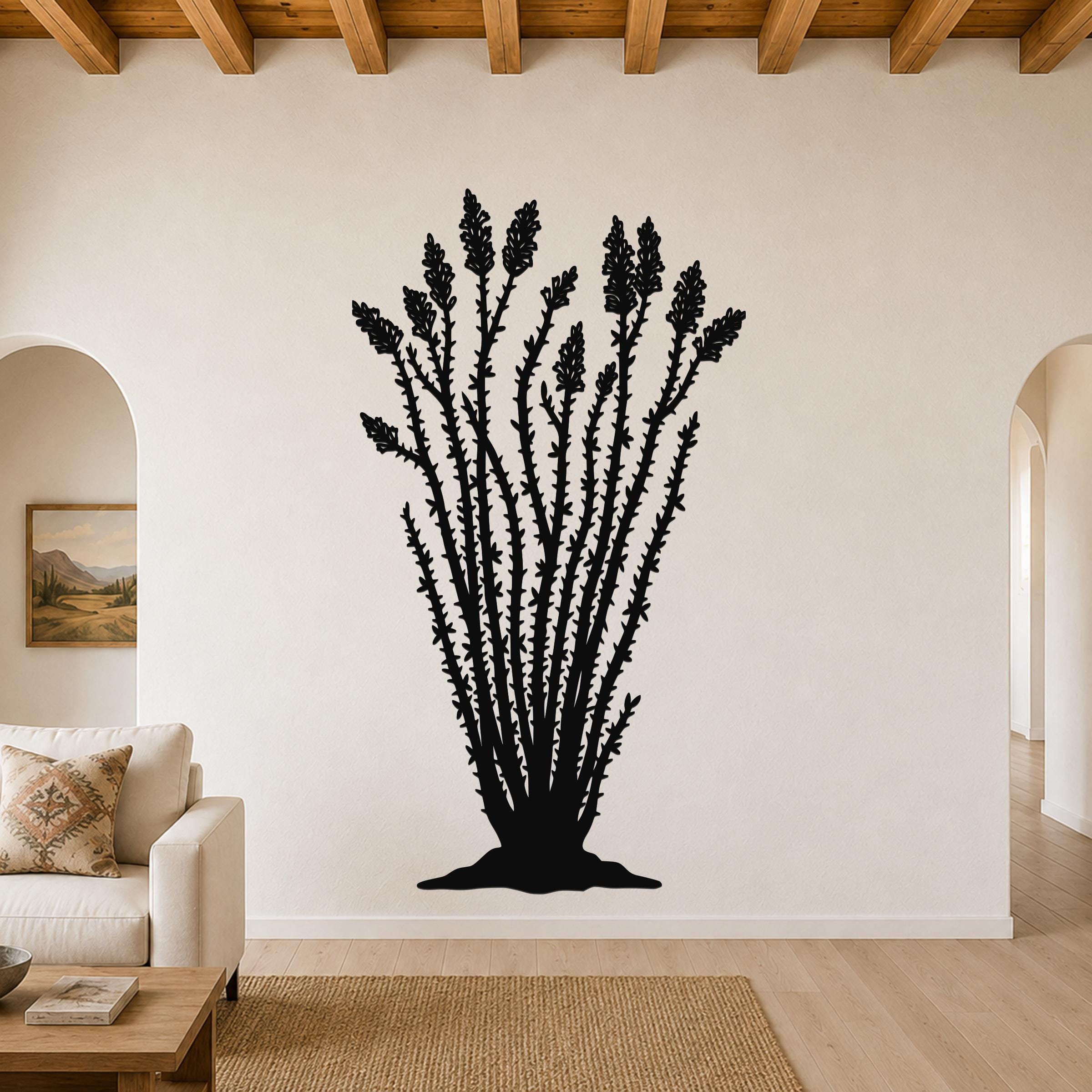 Black metal ocotillo wall art with detailed branch and flower cutouts, mounted on a living room wall above a sofa.