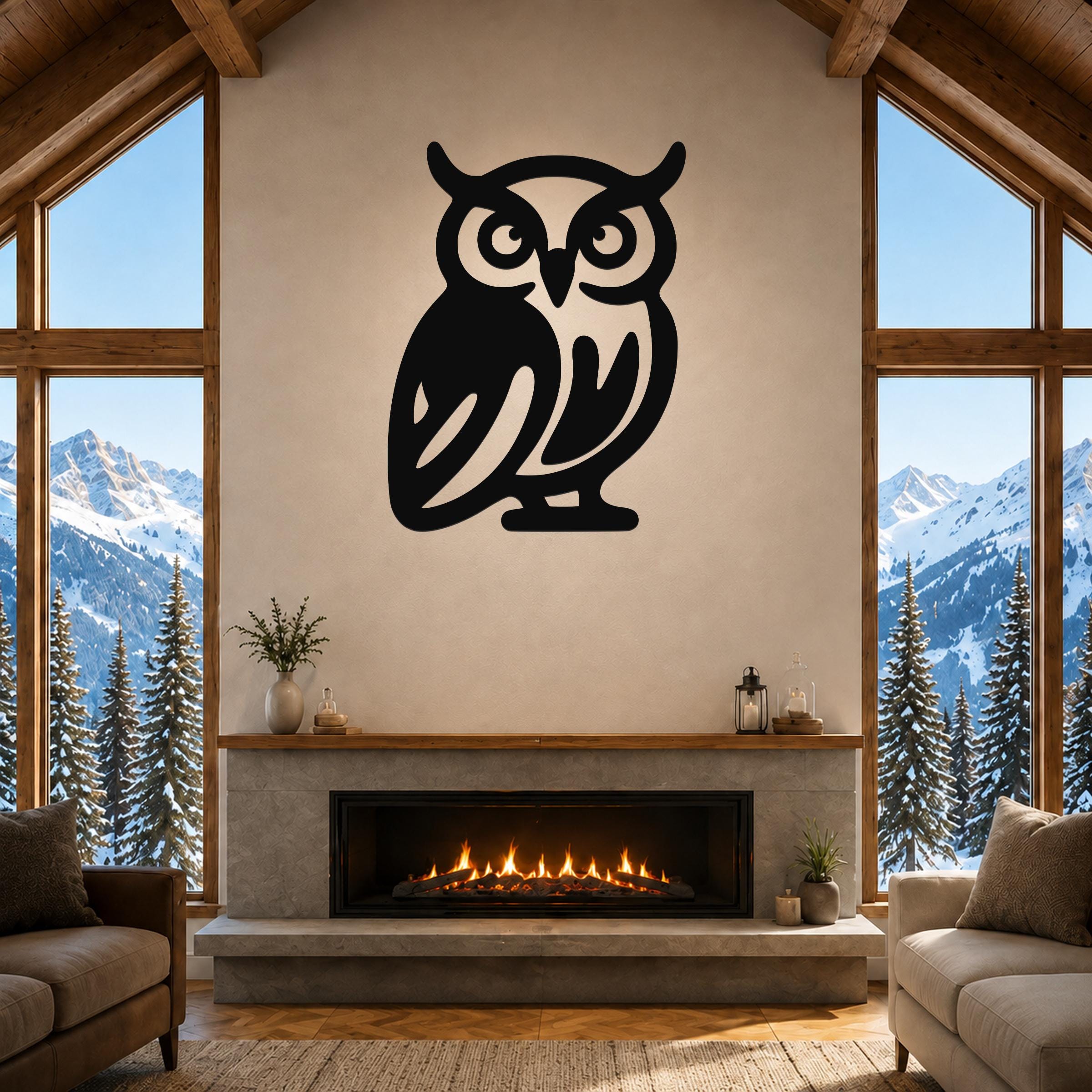 Black metal owl wall art with cutout details, mounted above a fireplace in a living room with large windows and mountain views.