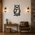 Black metal owl wall art in a silhouette style, perched on a branch, mounted on a shiplap wall above a wooden console table in a living room.