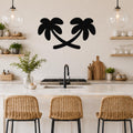 Black metal palm tree wall art with two silhouetted trees, mounted on a kitchen wall above a counter.