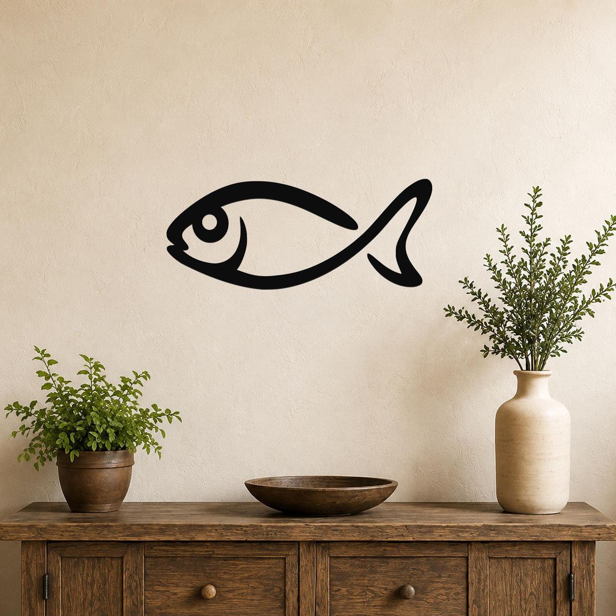 Black metal fish silhouette wall art mounted on a beige wall above a wooden console table with potted plants and a vase.