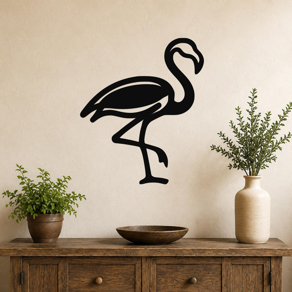 Black metal flamingo wall art silhouette mounted on a beige wall above a wooden console table with potted plants.